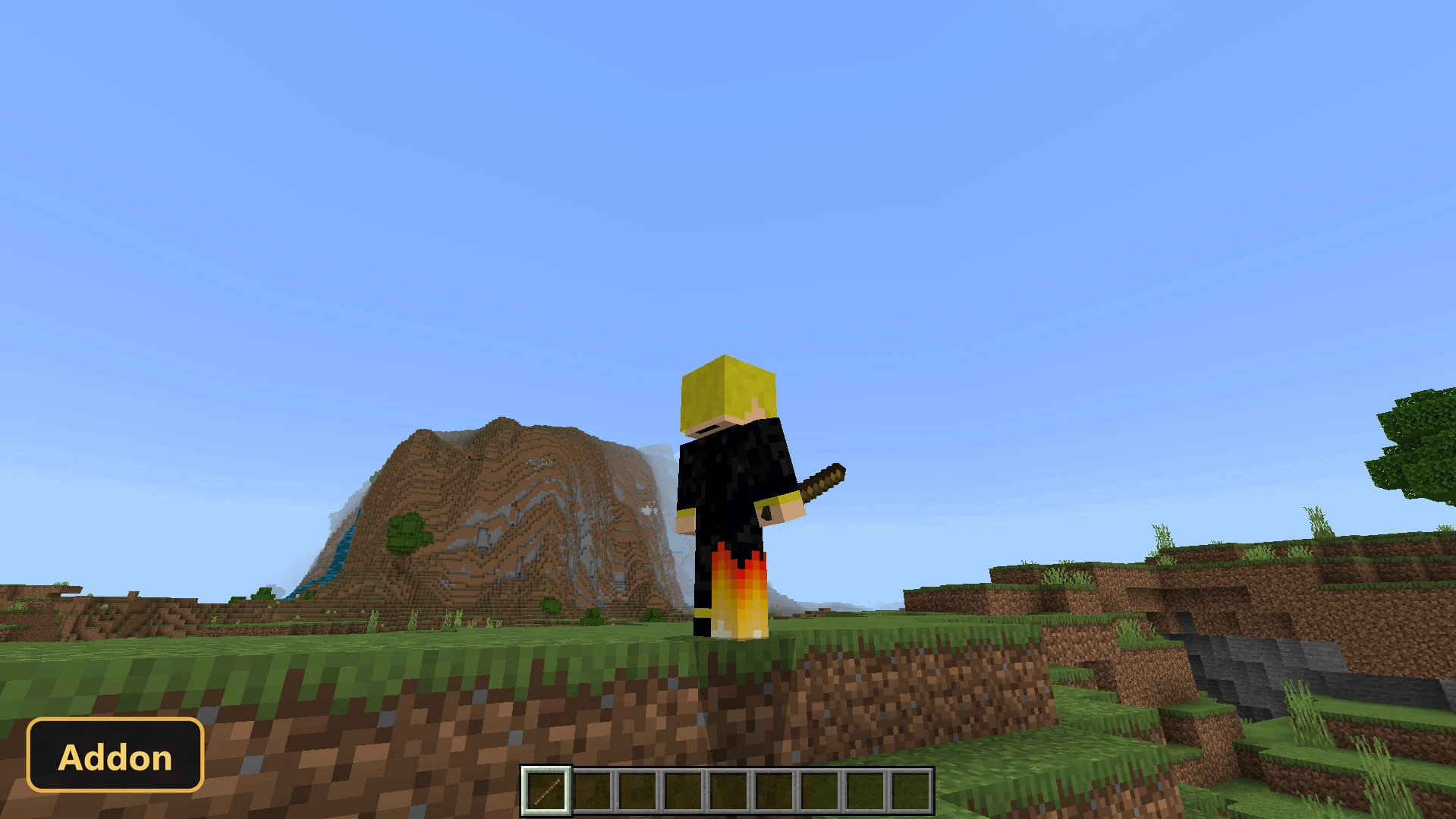 player standing on grassy hill, holding a stick, with mountains in background